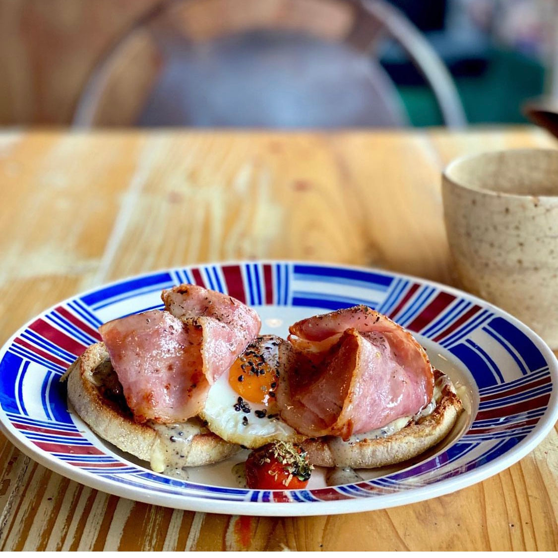A toasted English muffin with egg, bacon and a cup of coffee