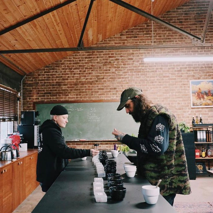 Two baristas cupping delicious single origin coffee at Dark Arts Coffee in London