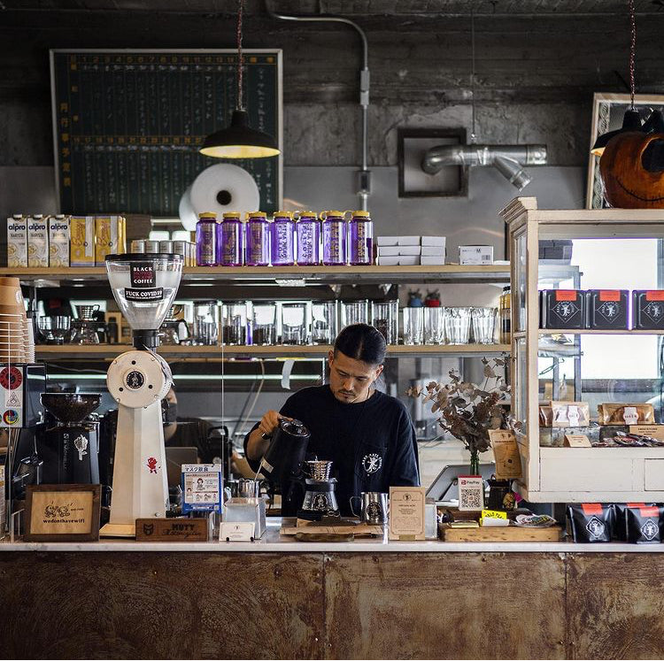 A barista skilfully preparing a filter coffee at the counter in the Dark Arts Coffee cafe in Hayma, Japan