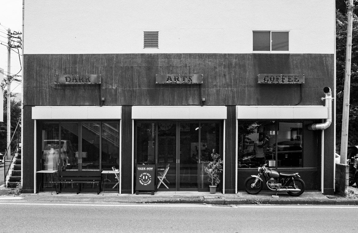 External shot of the Dark Arts Cafe in Hayama, Japan. There is outdoor seating and a cool motorbike in front of the cafe.